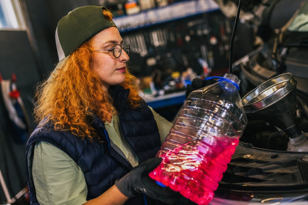 A student is inspecting the coolant for the car before winter maintenance