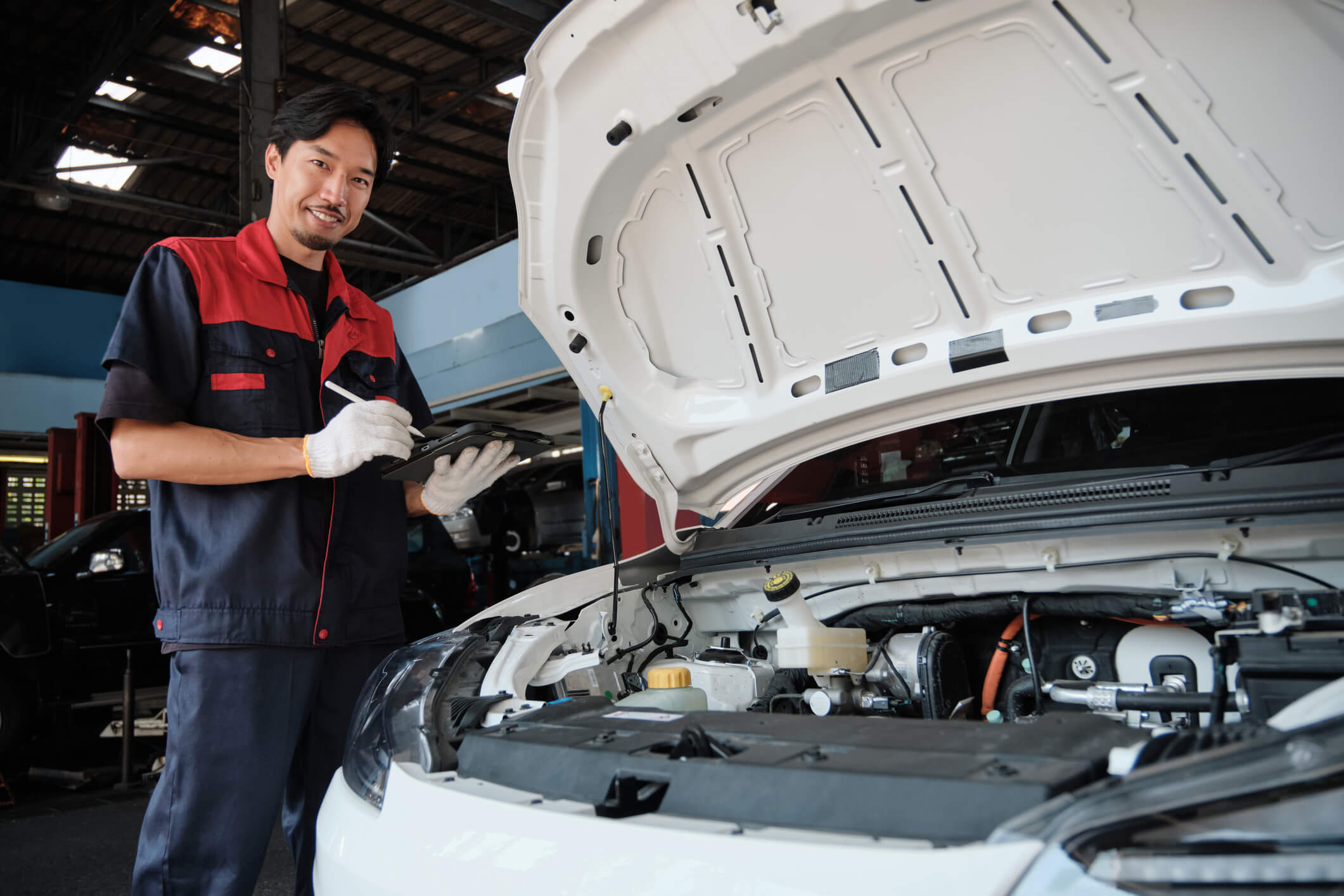 An automotive technician inspecting a hybrid vehicle in a repair shop
