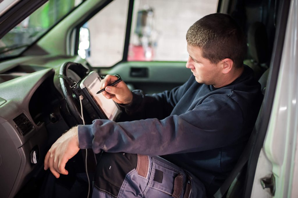 Apprentice mechanic practicing vehicle diagnostics in an automotive workshop
