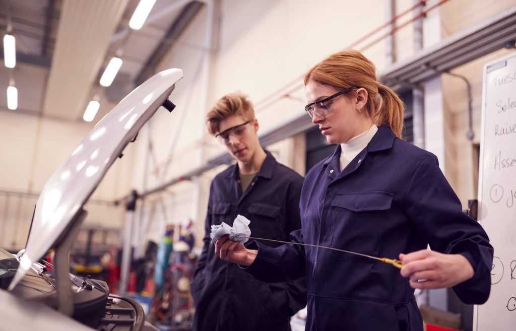 Automotive trainee performing an oil inspection in a hands-on training lab