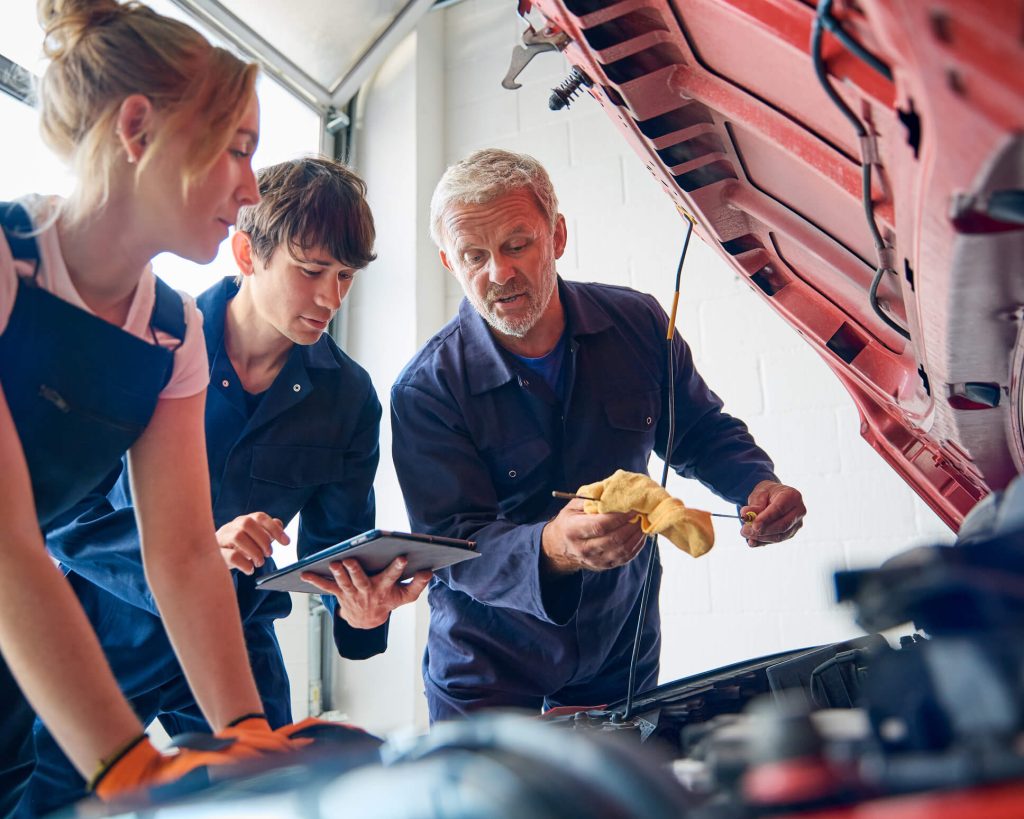 Instructor explaining transmission oil inspection to auto mechanic students