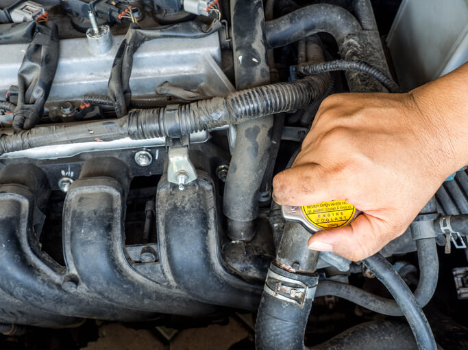 An auto mechanic testing an engine cooling system for coolant leaks