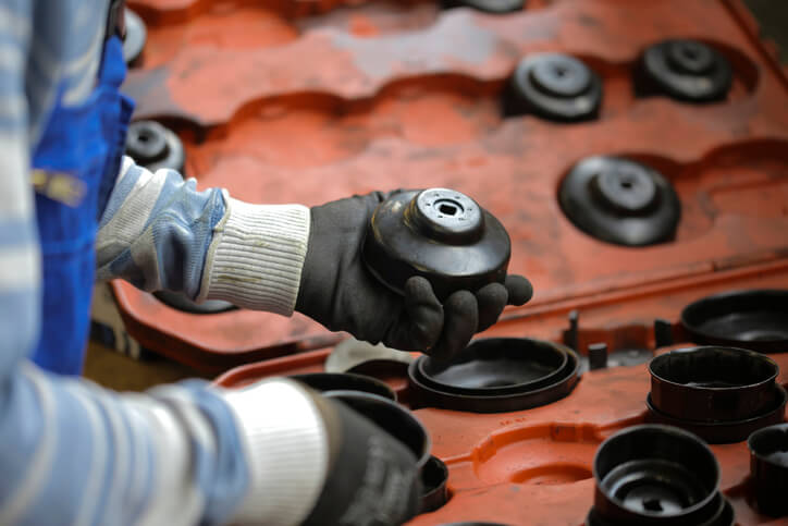 A technician checking an oil filler cap for milky residue