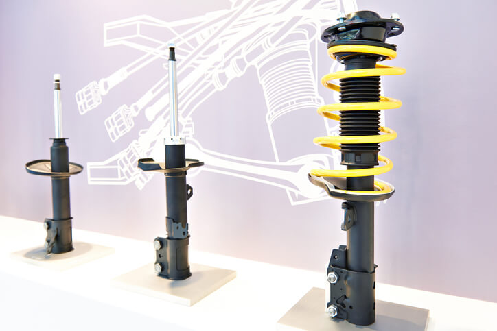 Close-up comparison of a vehicle shock absorber and suspension strut