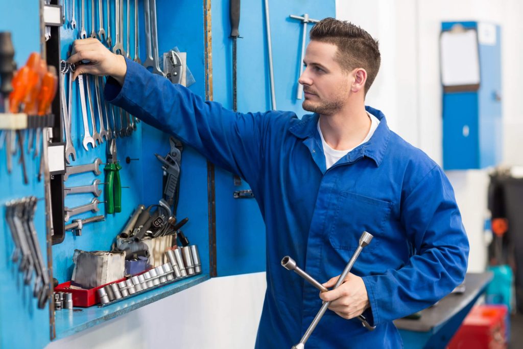 An entry-level automotive technician using hand tools in a training workshop