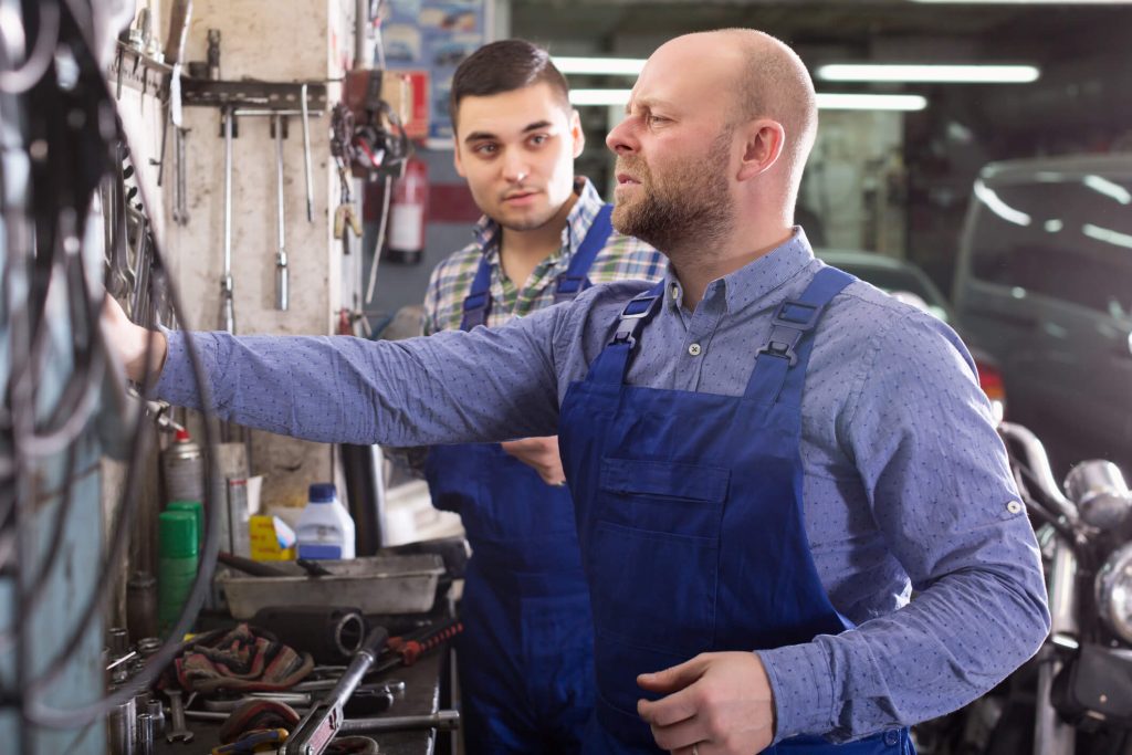 A mechanic instructor demonstrating proper tool selection and shop safety practices