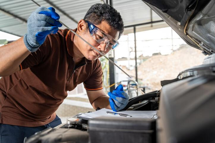 An auto mechanic checking transmission fluid level and condition in a workshop