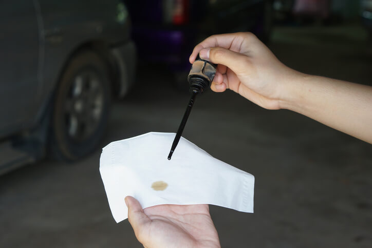 An auto mechanic inspecting transmission oil fluid before vehicle service