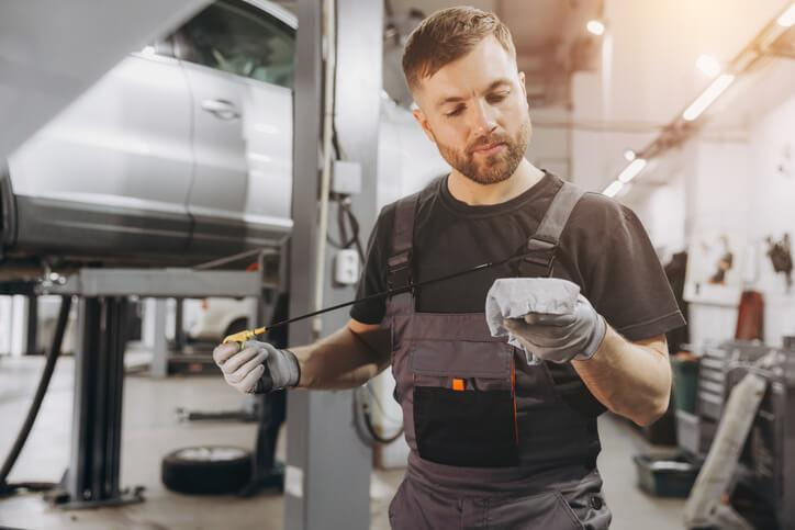 An automotive technician diagnosing dark transmission fluid during routine maintenance