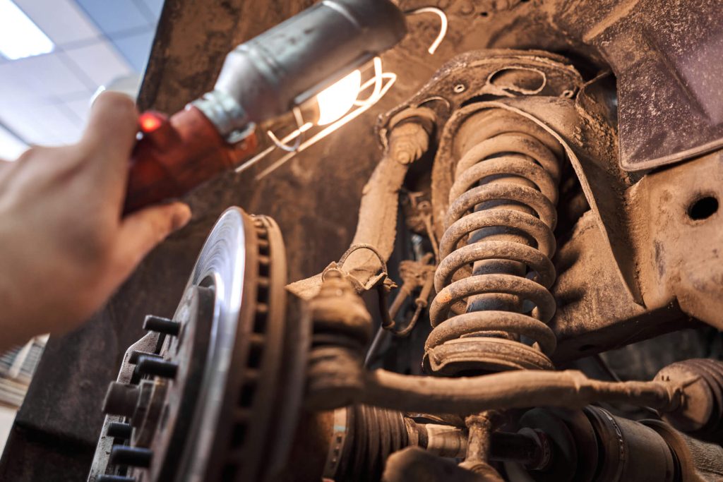 A close-up of a vehicle strut assembly being examined in an automotive workshop