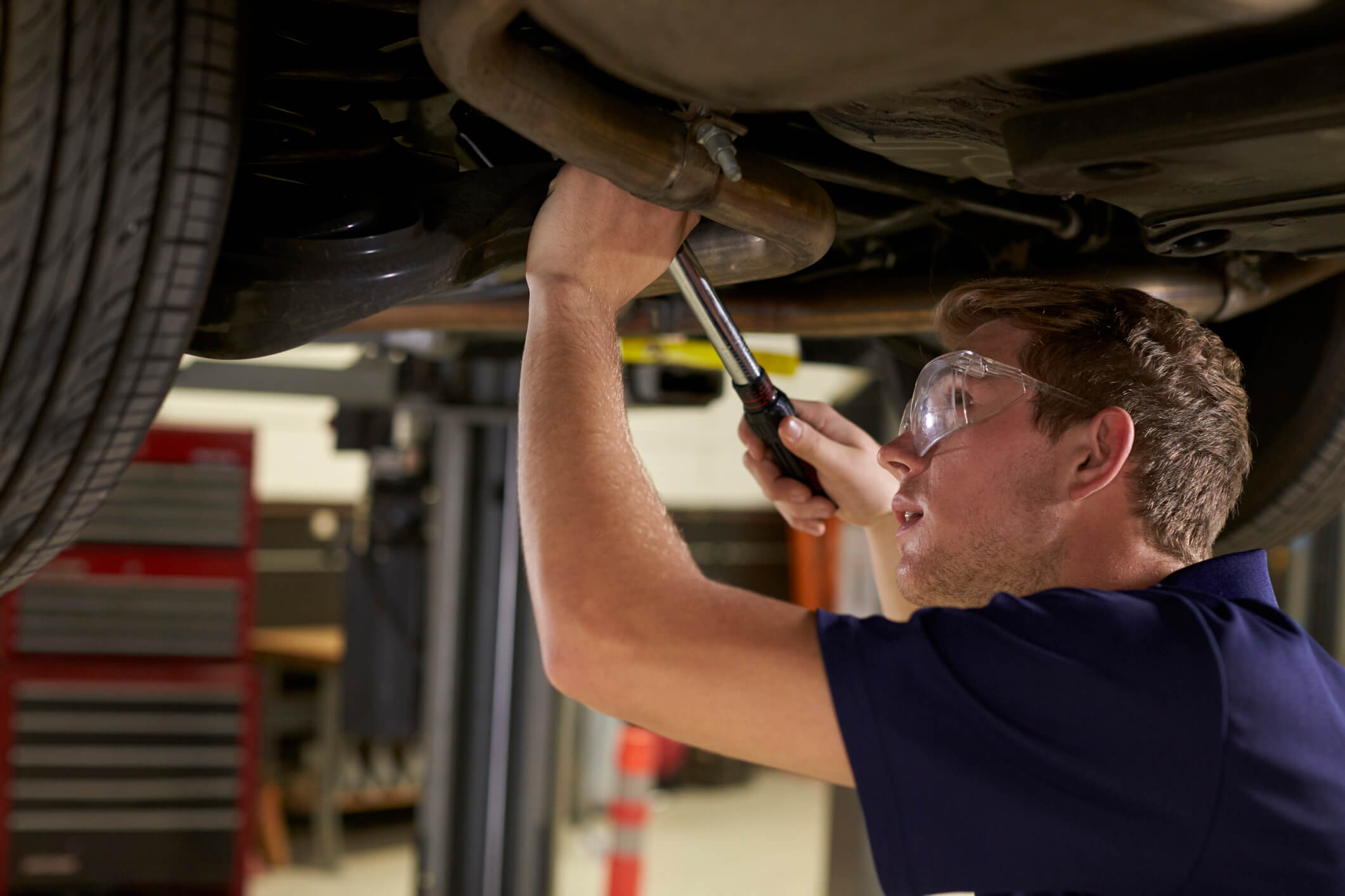 An automotive student inspecting a front suspension strut during hands-on shop training