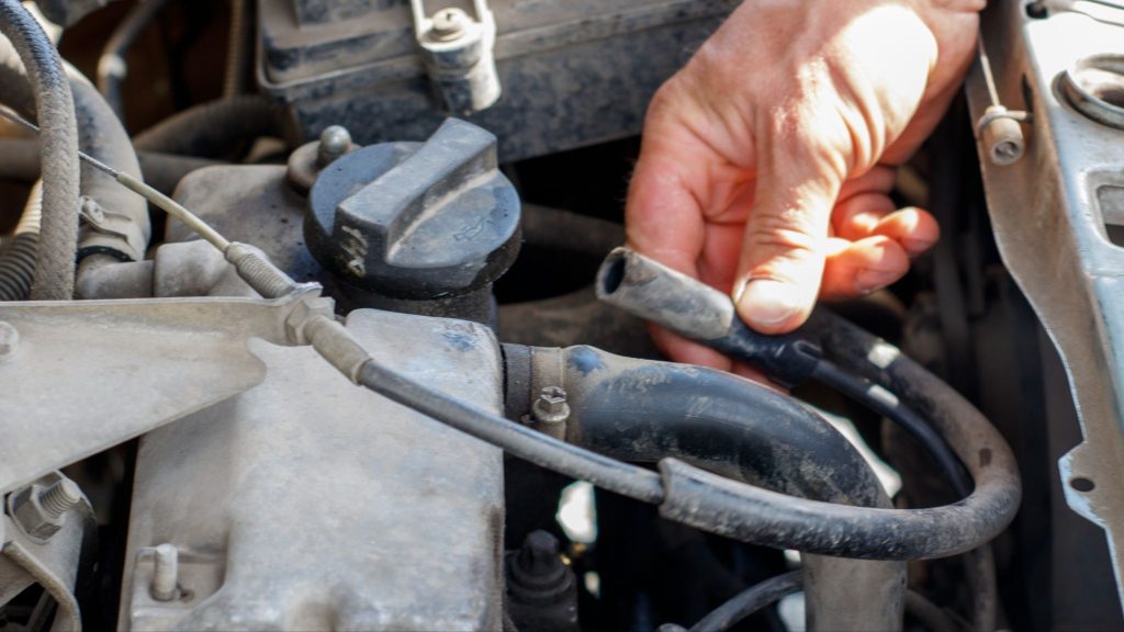 Mechanic inspecting a PCV valve and crankcase ventilation hose