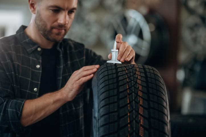 An auto mechanic checking winter tire tread depth at a Montreal service shop
