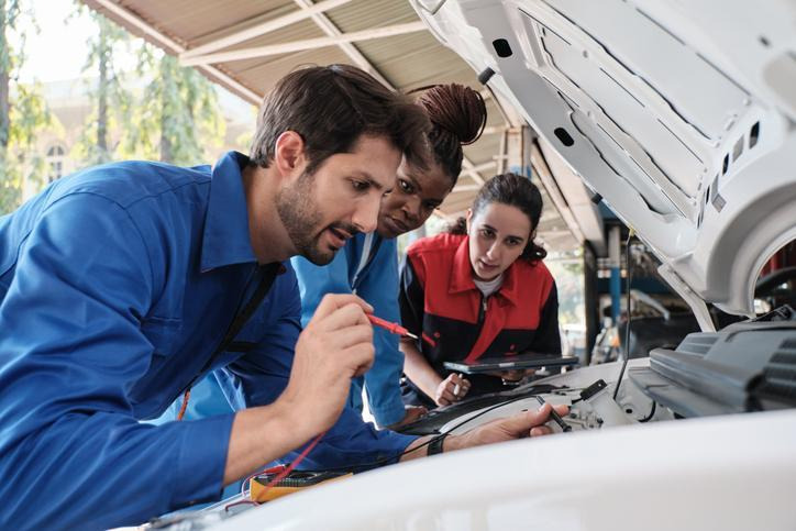 An automotive student learning high-voltage safety around an EV A/C system