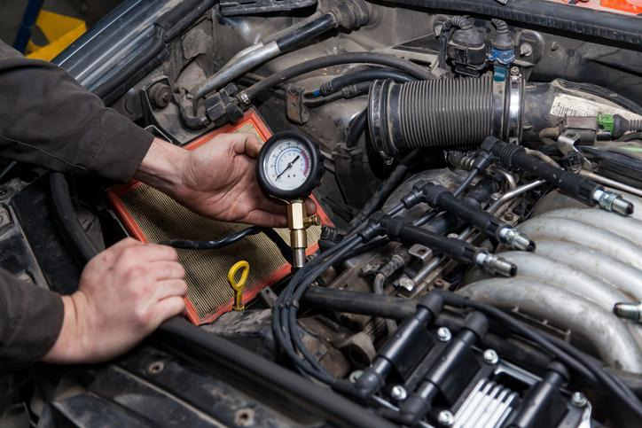 A technician connecting a fuel pressure gauge during engine diagnostics
