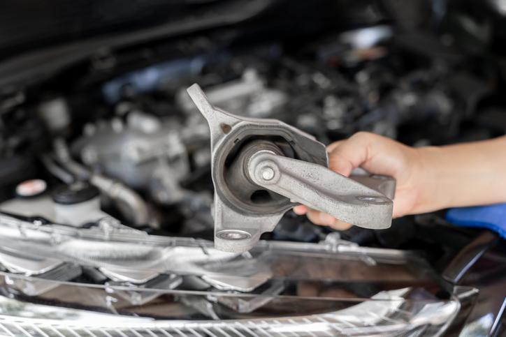 Automotive student checking a motor mount for cracks and excess movement