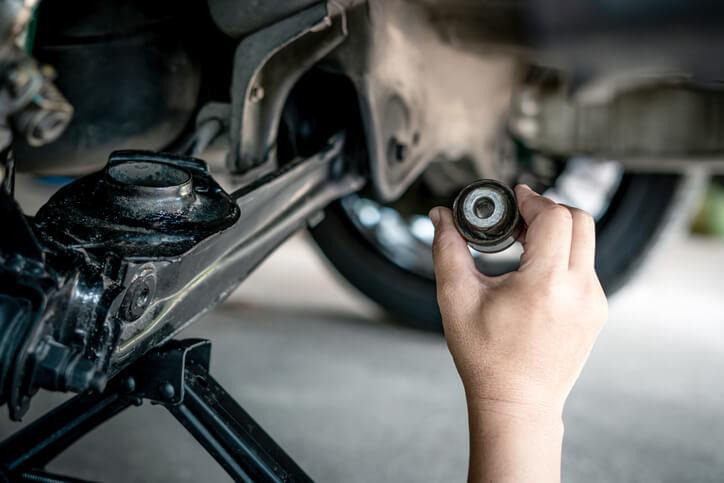 Automotive student checking a lower control arm bushing for wear