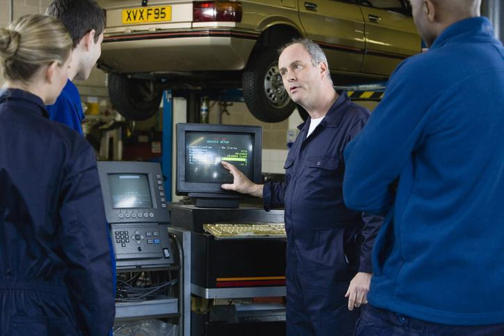 An automotive instructor explaining electrical diagnosis in a training shop