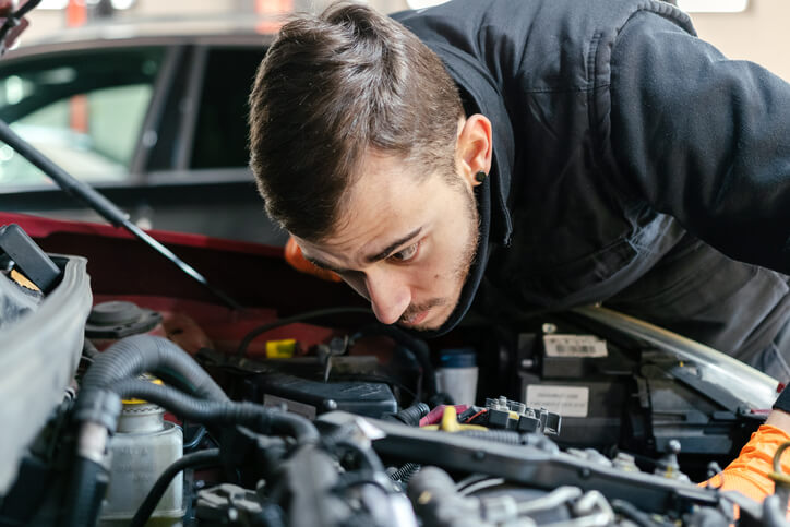 An automotive student inspecting an engine lubrication system