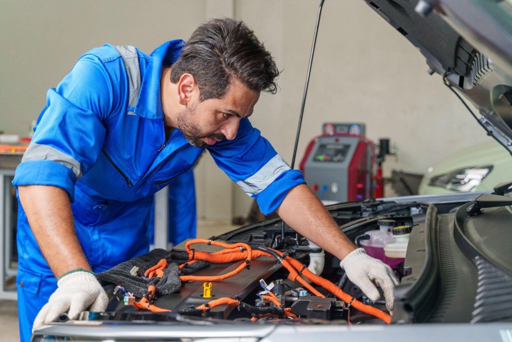 Technician performing plug-in hybrid maintenance in an automotive shop