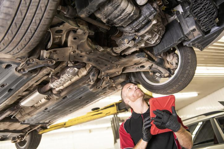 An automotive student performing suspension diagnosis after pothole damage