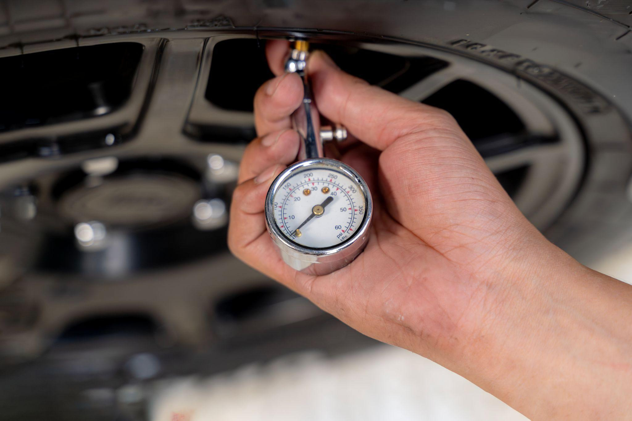 Automotive technician checking tire pressure with a pressure gauge