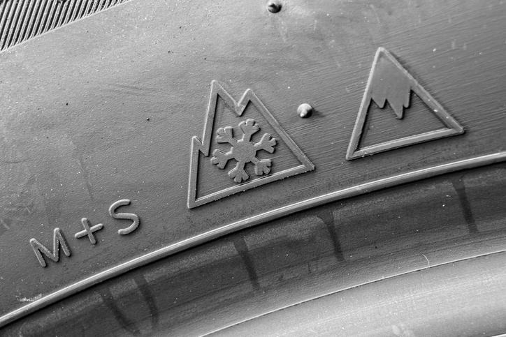 An automotive student inspecting the winter tire pictogram on a tire