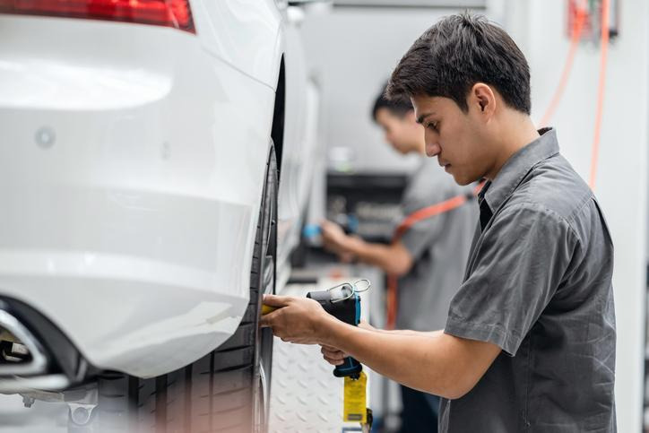 A technician measuring all four tires before an AWD tire replacement