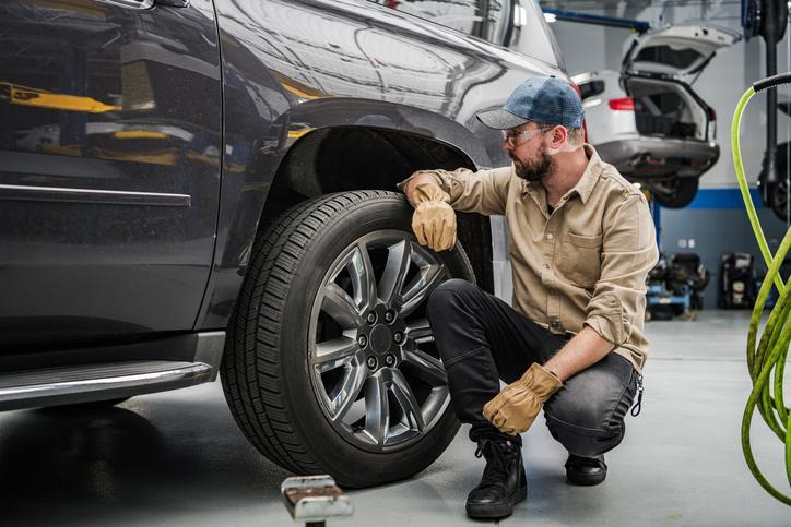 A mechanic inspecting mismatched tires on an all-wheel-drive vehicle