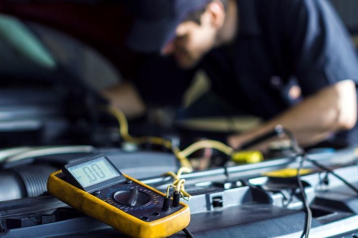 An automotive student testing a radiator fan relay with electrical equipment