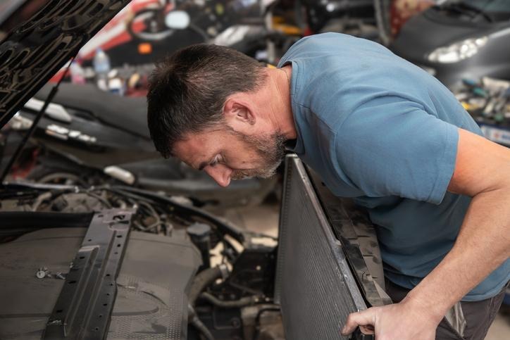 A technician inspecting wiring after finding a cooling fan not working