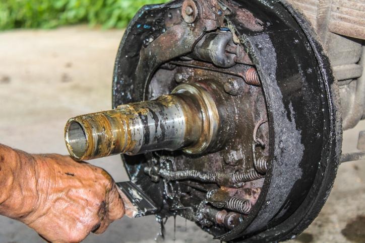 A technician checking wheel cylinder leaking symptoms behind a brake drum