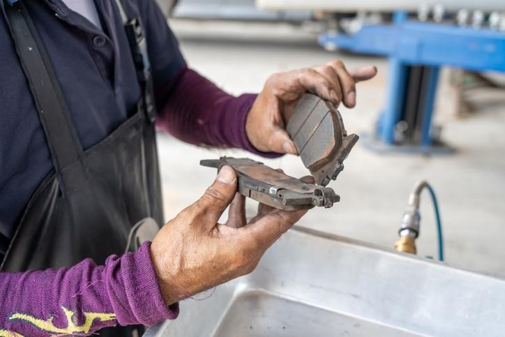 An automotive student inspecting brake shoes for hydraulic-fluid contamination