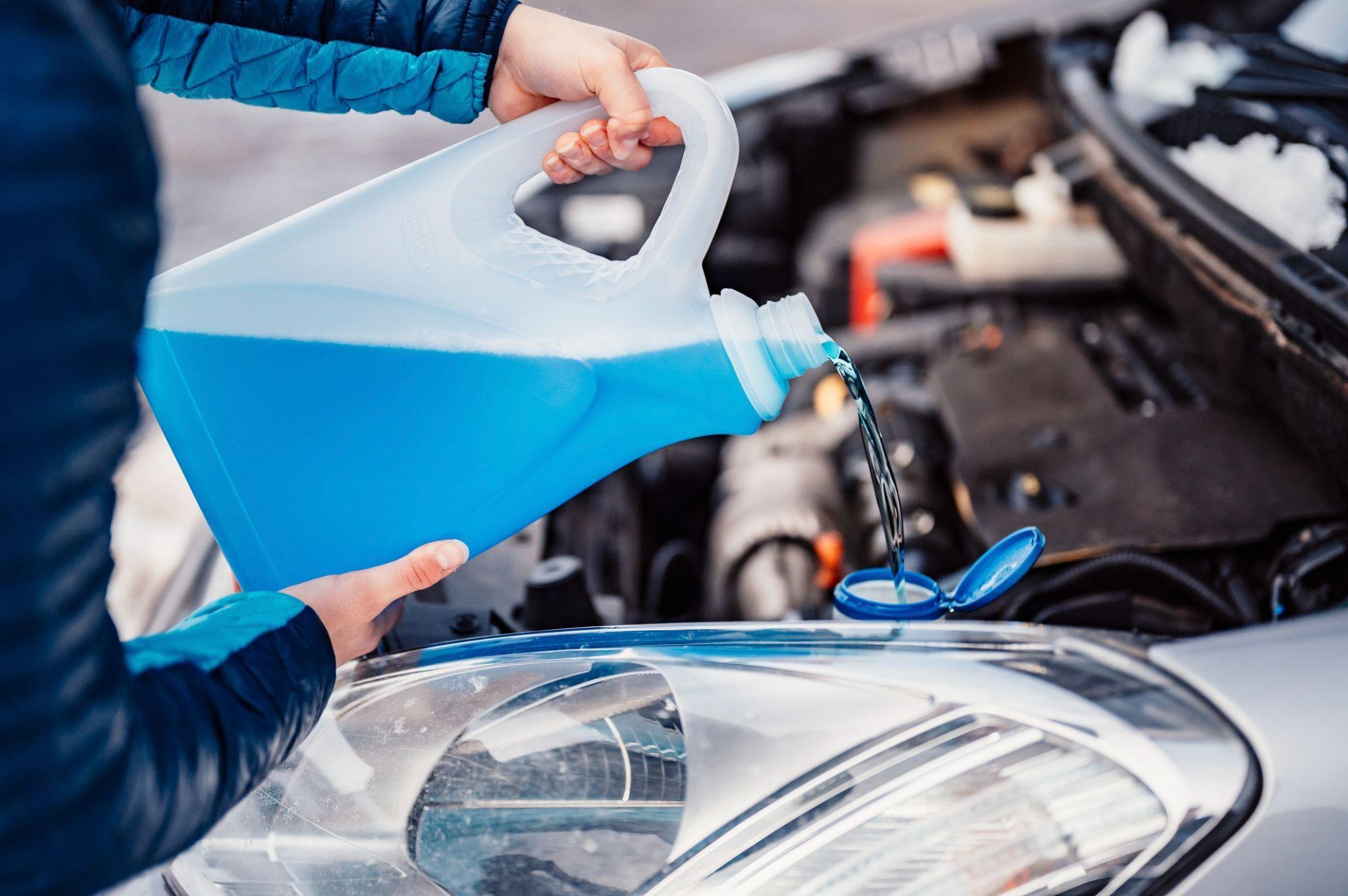 A student checking washer fluid for winter during fall vehicle maintenance
