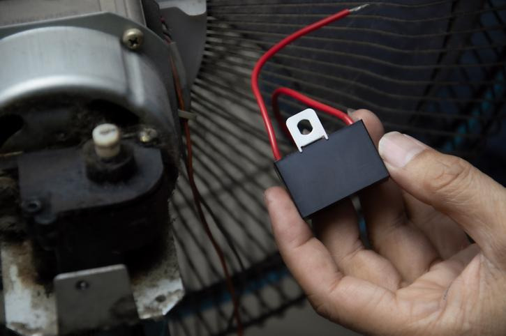 Technician inspecting a bad blower motor resistor and electrical connector