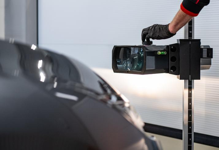 An automotive student performing headlight alignment on a vehicle