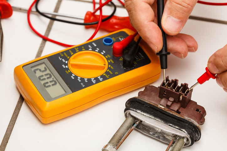 Technician using a multimeter to test an engine block heater circuit