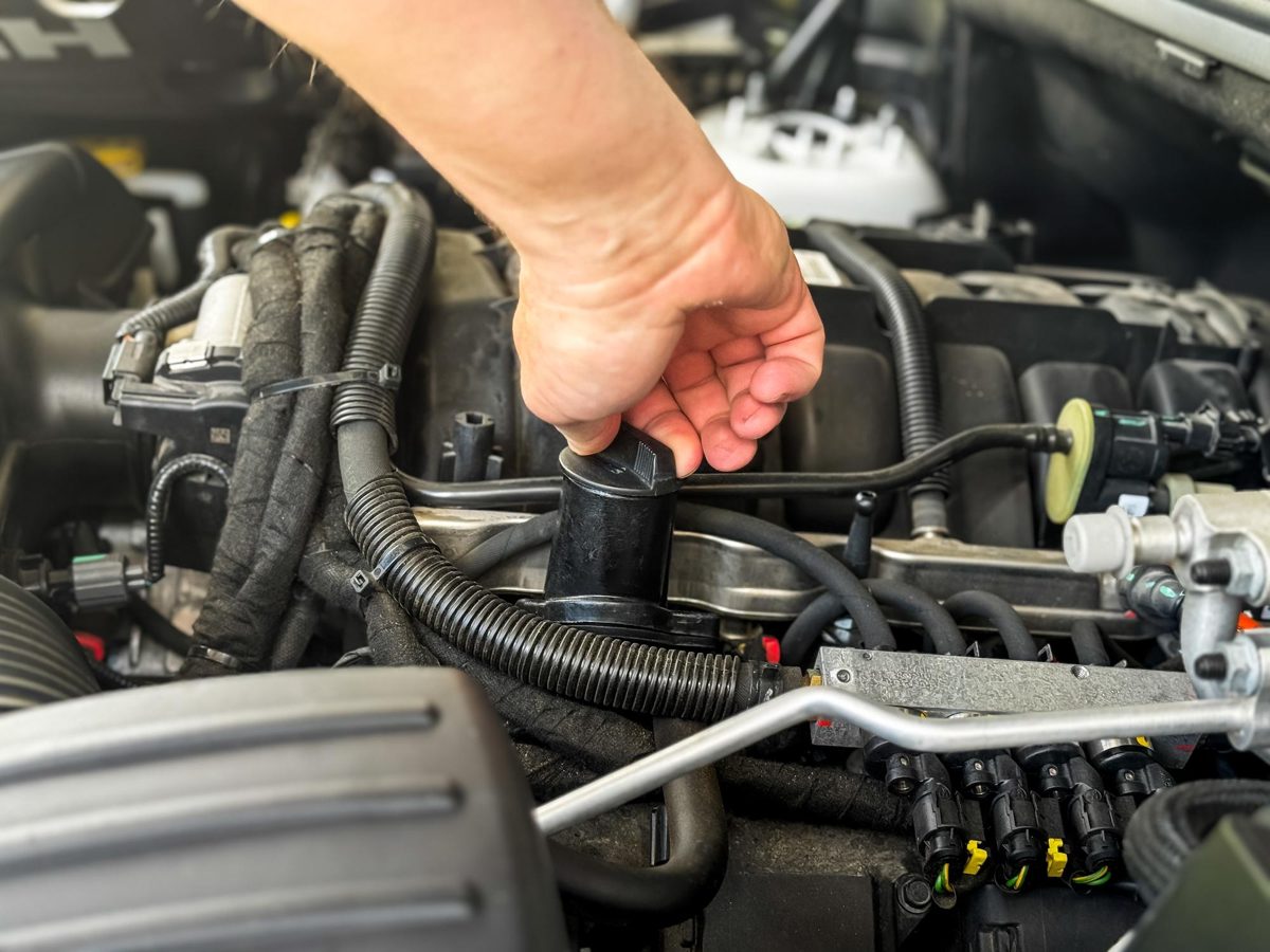 A technician inspecting an EVAP purge valve in an engine compartment