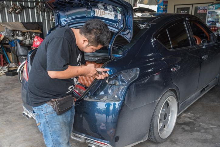 A technician carrying out a brake light inspection in a repair shop