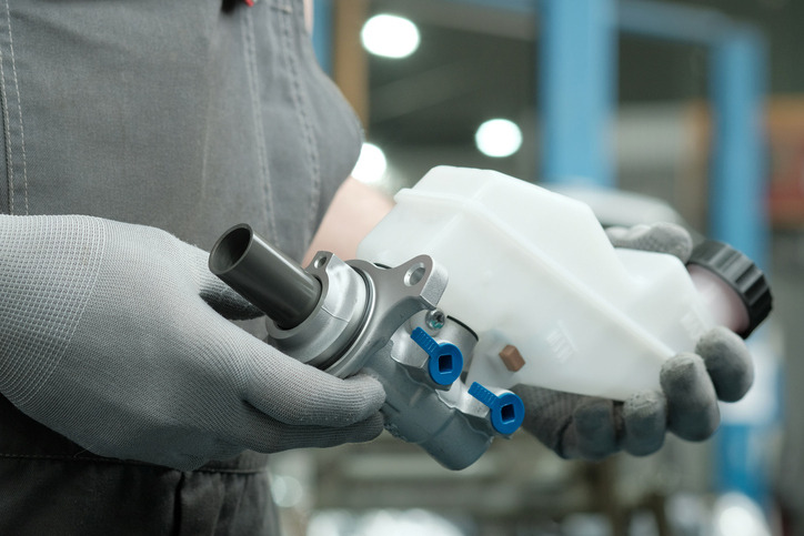 Automotive student checking a brake master cylinder for hydraulic fluid leaks