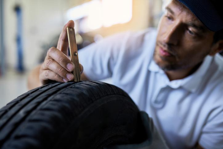 An automotive student using a tire tread depth gauge