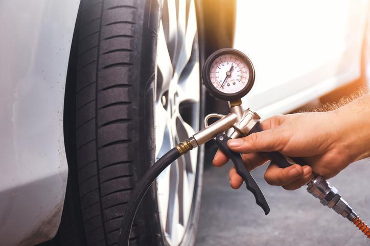 A mechanic inspecting tire wear and pressure before heavy rain