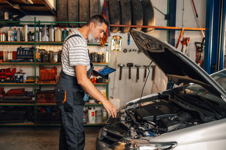 An automotive student using a diagnostic scan tool to examine hybrid vehicle systems