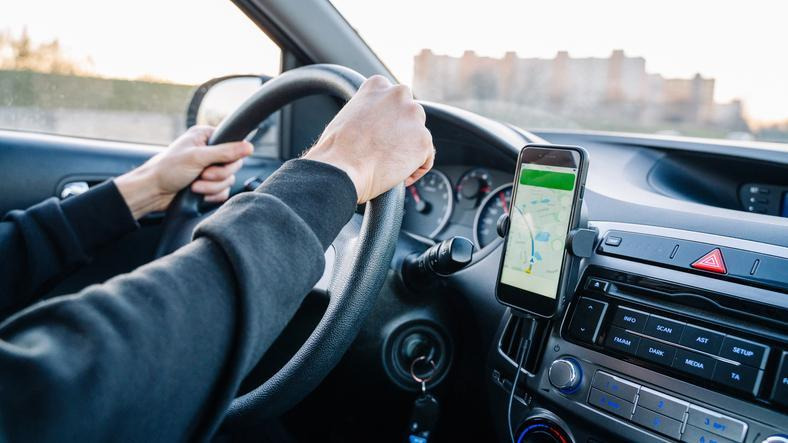A driver using a smartphone to locate an available public EV charger