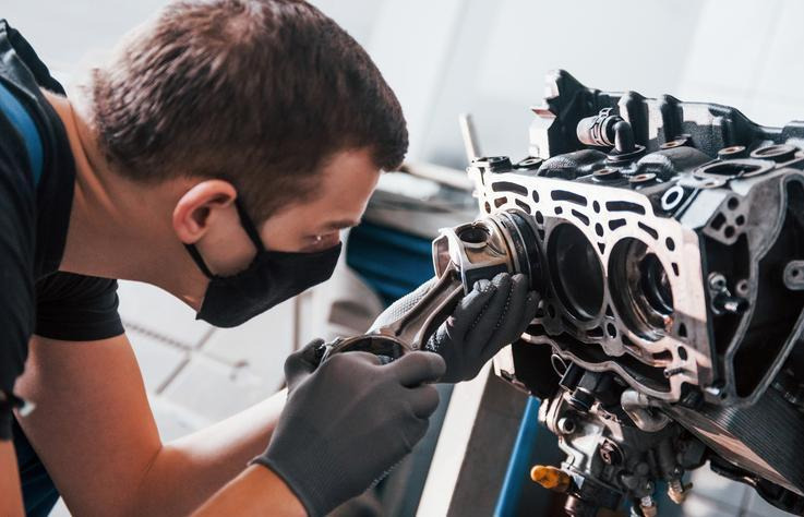 An automotive student examining engine components during hands-on training