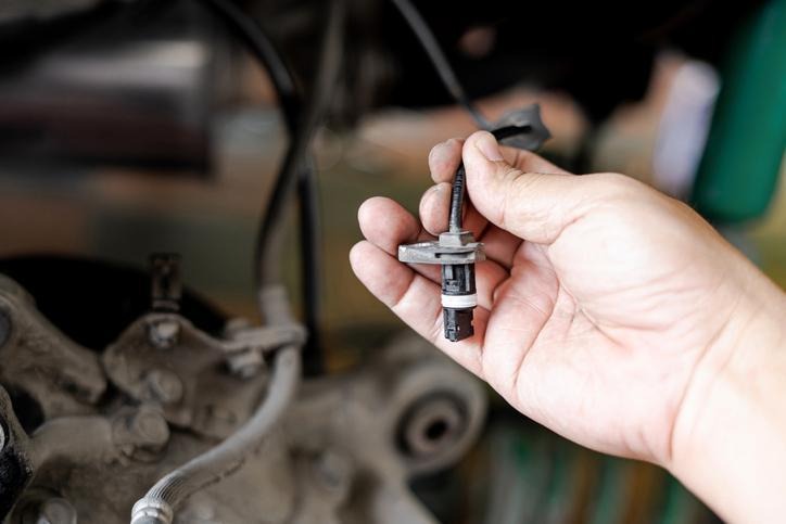 A technician inspecting an ABS wheel speed sensor and wiring near the hub
