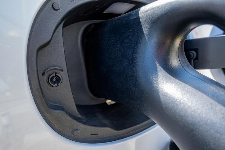 A close-up of an electric vehicle charging plug and charge-port locking mechanism