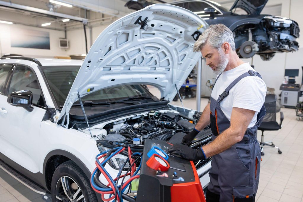 A technician checking the specified electric compressor oil before an A/C repair
