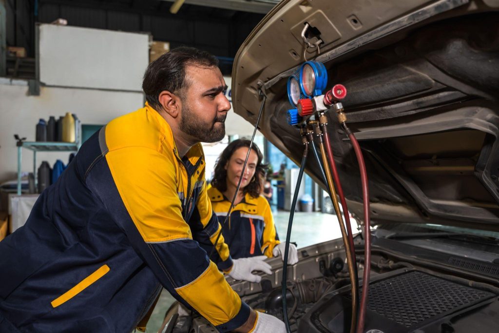 An automotive student learning safe high-voltage A/C compressor service