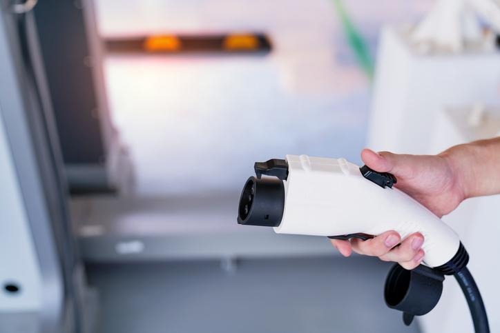 A technician examining an EV charging connector for heat damage